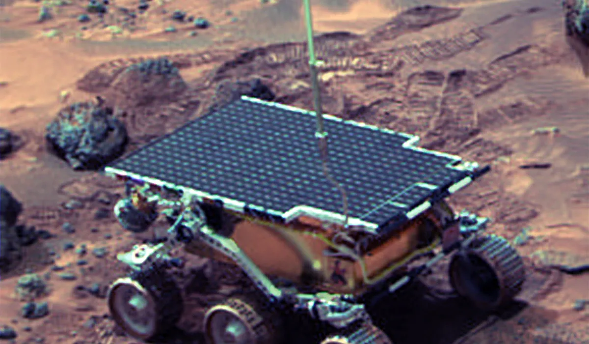 Sojourner rover on the Martian surface next to a large rock, photographed from the Pathfinder lander camera